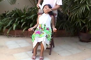 Asian teen tied up and hand cuffed on a chair